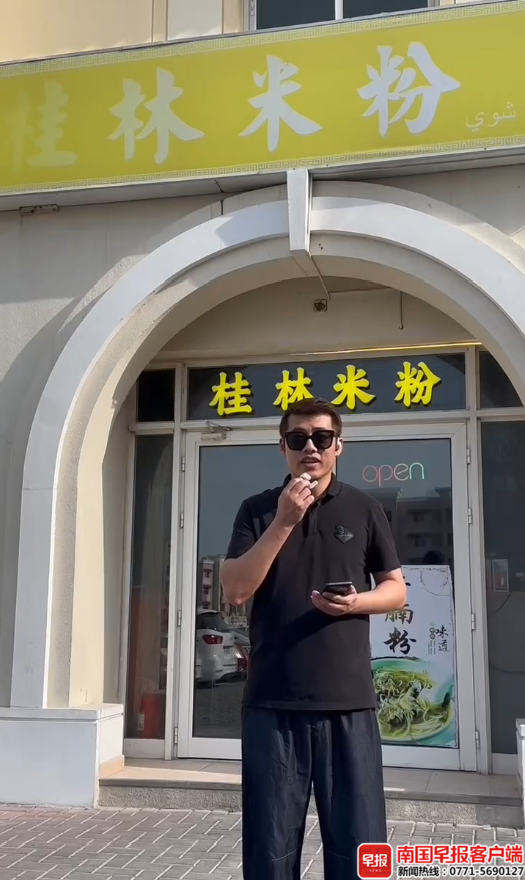 廖飞宇在自己的店铺门前向关心他们的人报平安。