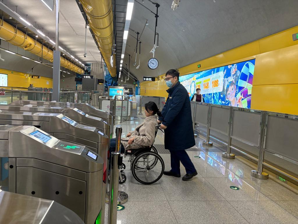 青岛地铁6号线工作人员服务特需乘客进站。新华社发