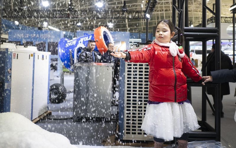 2026年1月6日，在2026哈尔滨国际冰雪经济博览会冰雪装备展区，小朋友触摸制雪机现场制造的雪花。新华社发（张春雷 摄）