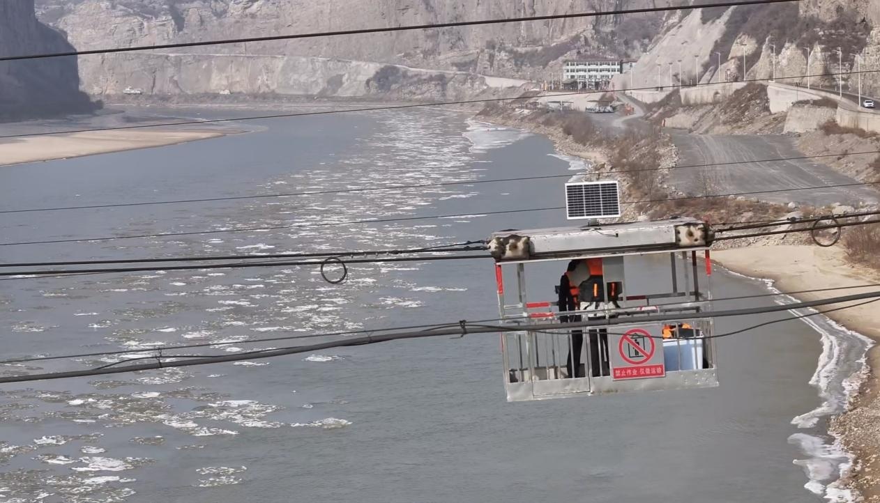 横跨东西两岸的钢索吊箱正在把人运往龙门水文站