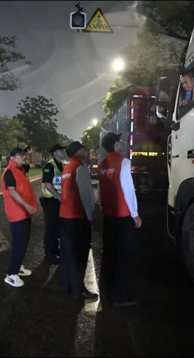 7月11日晚，孙如意（左一）劝导集卡司机前往安置点。 澎湃新闻记者 张呈君 图