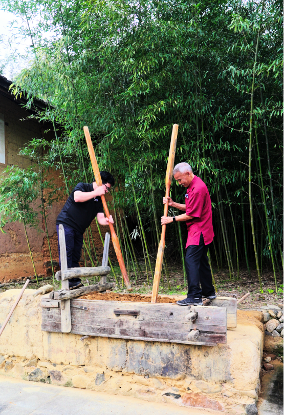 记者跟随张民泰（右）体验土楼夯土墙古法制作。蔡理昕 摄