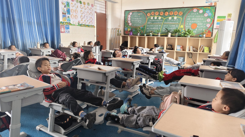 荣昌区龙集镇中心小学，学生们在可躺式课桌椅上午休。受访者供图