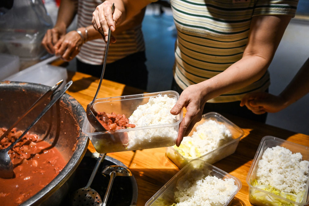 7月10日，在广西贵港市，后勤保障人员为一线救援人员准备餐食。新华社记者 曹祎铭 摄