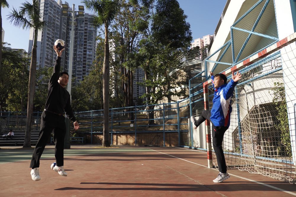 在香港新蒲岗彩虹道150号的露天游乐场，香港男子手球队主教练许文邦和队长谢永辉（左）在打手球（2025年12月17日摄）。新华社发（王申摄）