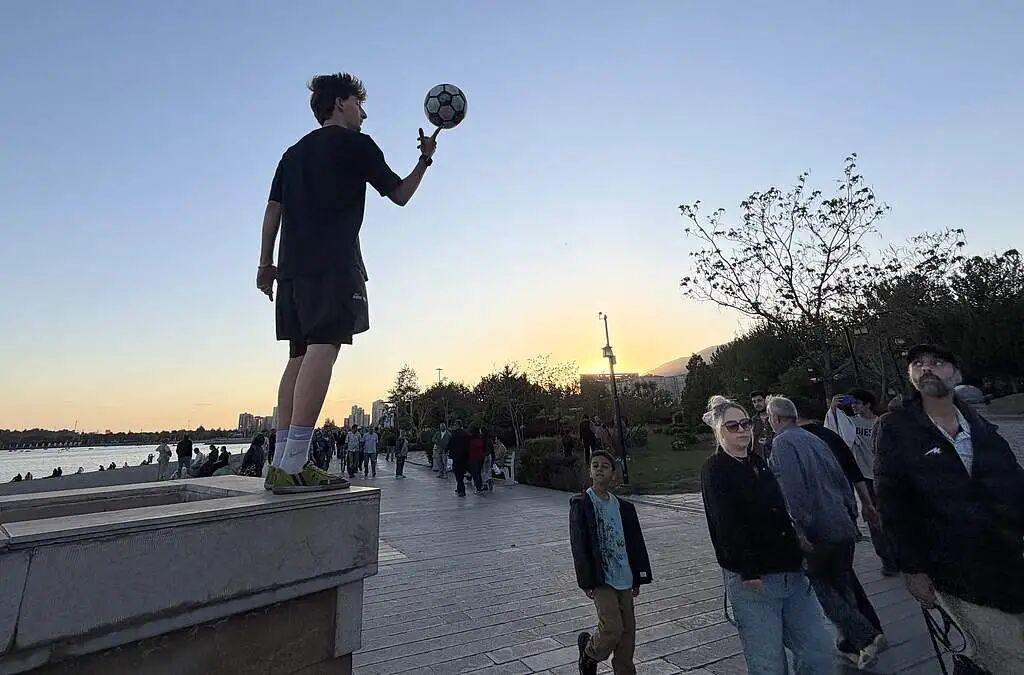 当地时间2026年4月26日，伊朗德黑兰西北部，一名少年在奇特加尔湖边踢足球。图/视觉中国