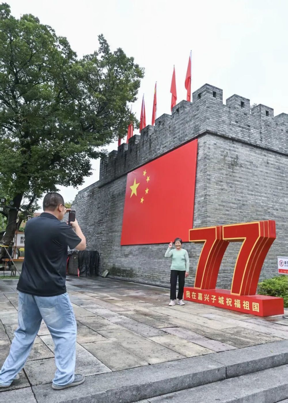 10月1日,游客在浙江嘉兴子城遗址公园与祝福祖国的装置合影。新华社记者 徐昱 摄