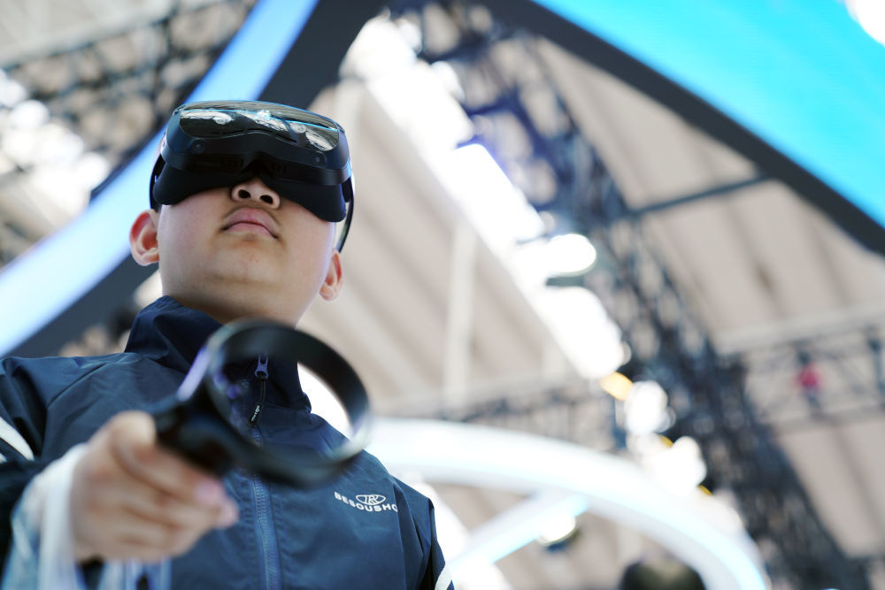 2025年5月18日，小朋友在哈尔滨举办的第三十四届哈洽会上体验AI与VR技术结合的冰球项目智能眼镜。在本届哈洽会上，主办方设置了冰雪经济展区，集中展示黑龙江的冰雪经济最新成果和应用场景。