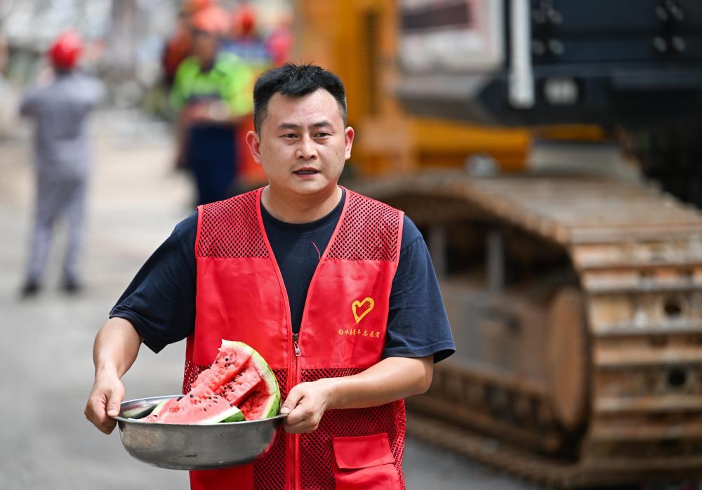 7月18日,志愿者为重庆彭水县山体崩塌救援现场的救援人员送来西瓜。