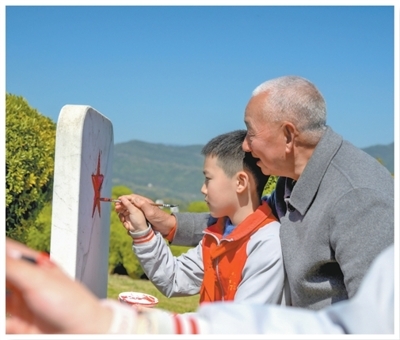 王建刚与通江李先念红军小学少先队员一起为无名烈士纪念碑描红。