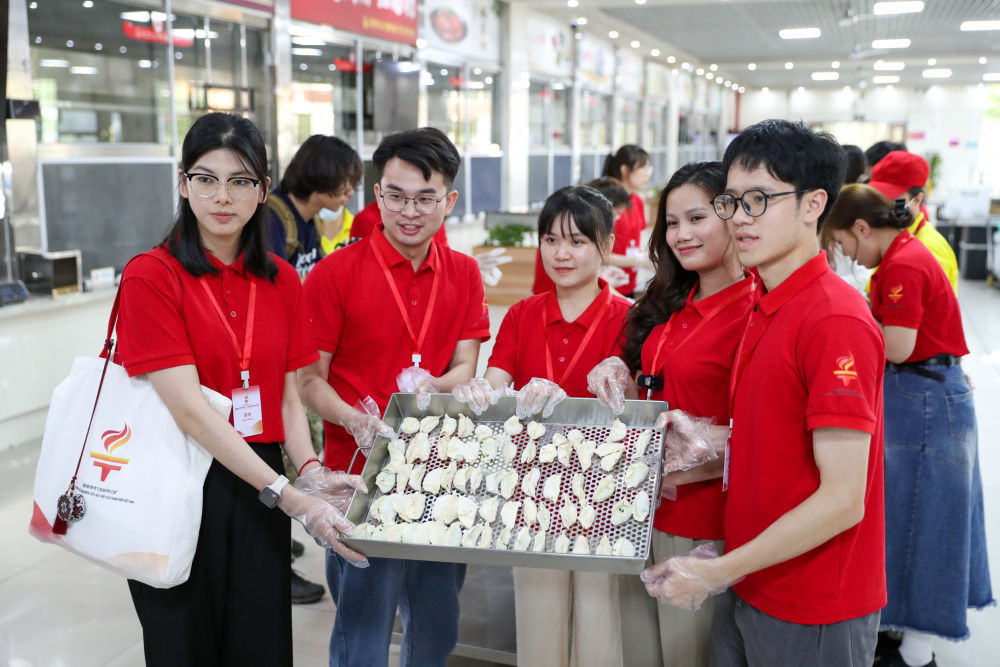 2025年5月19日，参加“红色研学之旅”的越南青年在广西师范大学食堂展示包好的饺子。新华社记者 李旭伦 摄