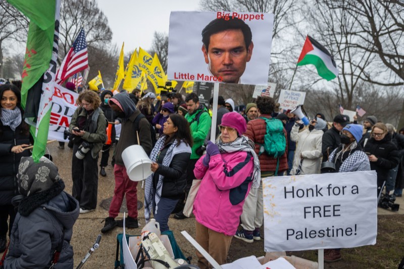 当地时间2026年2月19日,美国华盛顿特区,“和平委员会”首次领导人会议期间,抗议者在会议现场外举牌抗议。 IC Photo