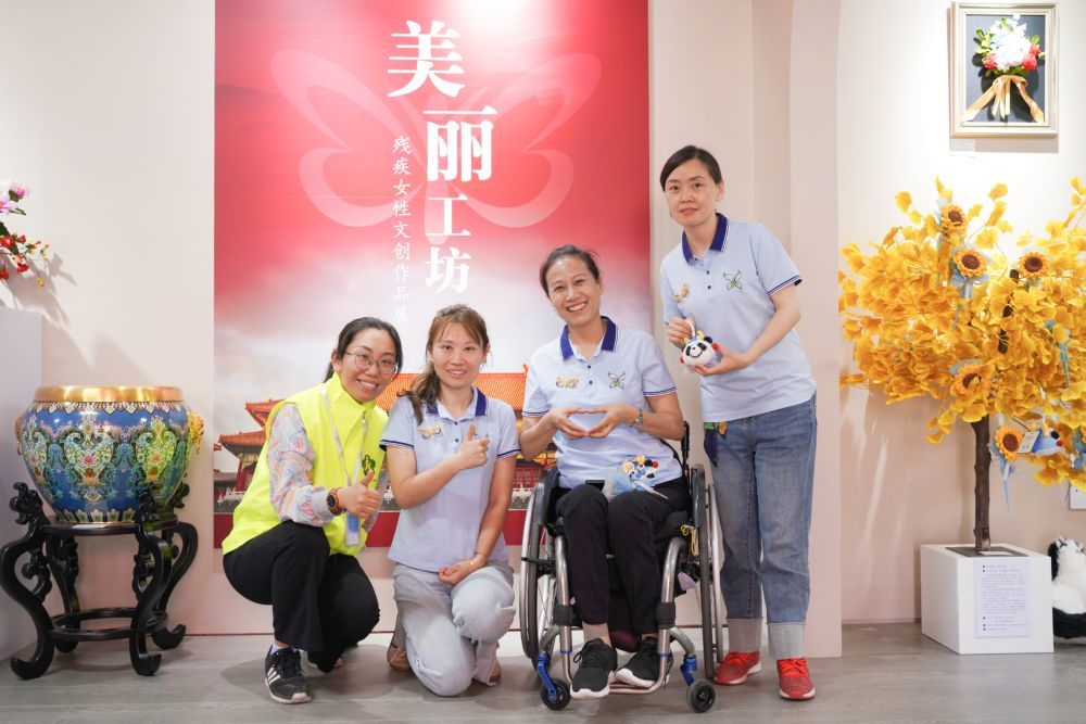 北京新生命养老助残服务中心主任唐占鑫(右二)团队在“美丽工坊”残疾女性文创作品展上。(受访者供图)