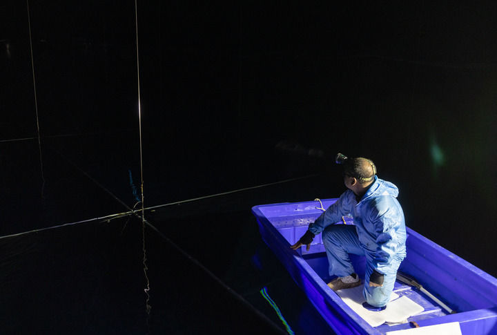 在位于四川省稻城县海子山的高海拔宇宙线观测站“拉索”水切伦科夫探测器阵列水池，科研人员坐船更换实验设备（2023年4月21日摄）。新华社记者 金立旺 摄