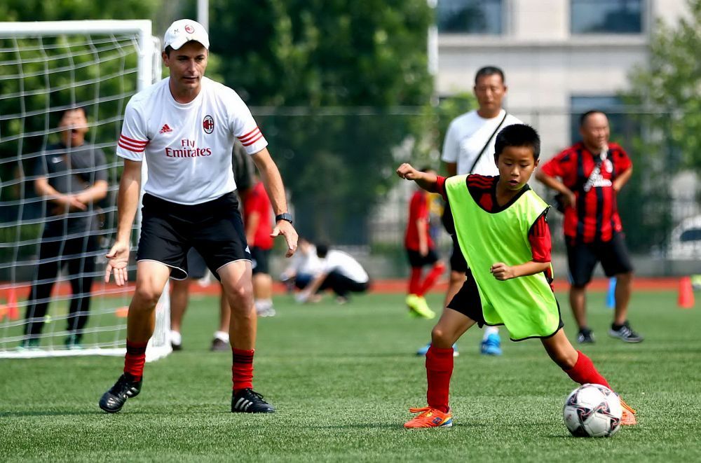 2016年7月28日，AC米兰足球俱乐部专业足球教练托马斯（左）在指导学生训练。当日，北京市大兴区魏善庄镇教育委员会与意大利AC米兰足球俱乐部中国青训营合作开展的校园足球培训项目在魏善庄中学开营。