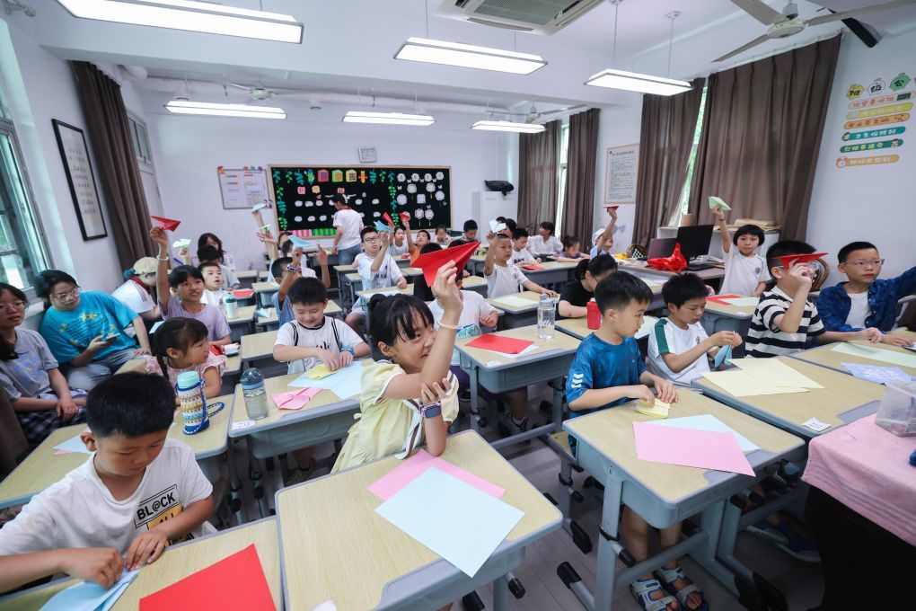 2026年7月9日,孩子们在浙江诸暨东白湖镇斯民小学教室里学习制作纸飞机。新华社记者 徐昱 摄
