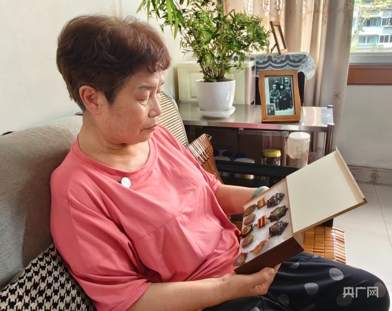 王英看着父亲王道金的勋章回忆过往（央广网记者 栾小琳 摄）