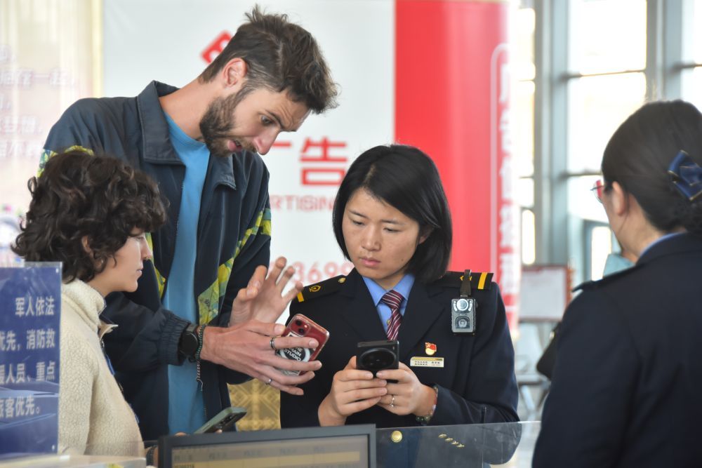 ↑ 2月16日，在云南红河站，铁路工作人员龚岸敏（右二）为旅客提供咨询服务。新华社发（薛莹莹摄）