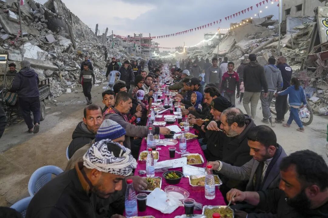 ◆2025年3月1日,加沙地带南部城市拉法,巴勒斯坦人在斋月第一天共进开斋饭,周围遍布被毁建筑。