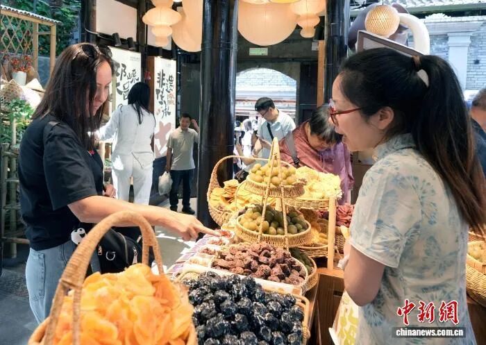 “五一”假期,成都宽窄巷子景区迎来旅游高峰。图为外国游客选购特色产品。中新社记者安源摄