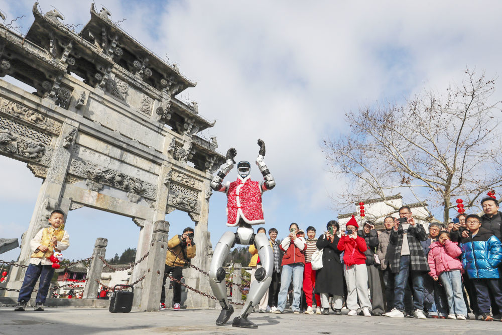 2月18日,游客在安徽省黟县西递古村观看机器人表演。新华社发(施亚磊 摄)