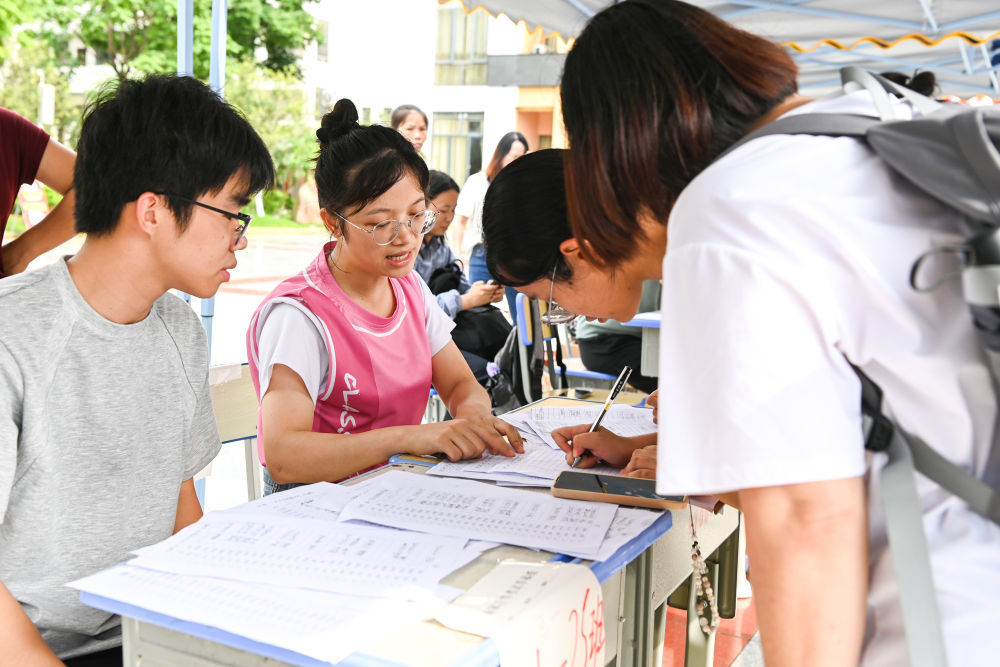 ↑ 7月8日,在广西贵港市一处临时安置点,学校老师指导学生和家长填写信息。新华社记者 曹祎铭 摄