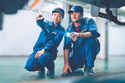 蓬皮蒙·蒙占迪(左)与同事在万象机辆运用检修车间检查列车车底。刘莹嘉摄