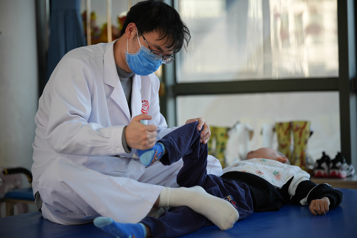 2月5日，一位福利院的老师正在给孩子进行肢体康复训练。新华每日电讯记者谢晗 摄