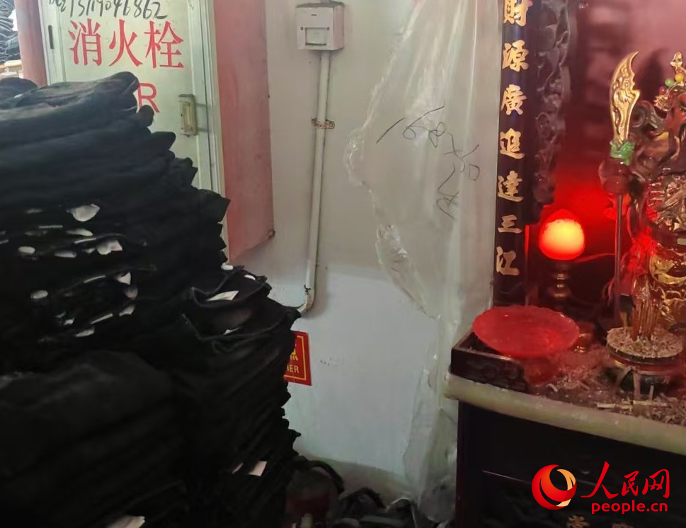 消火栓被牛仔裤挡住，旁边还有在燃烧的香火。人民网记者 王子锋摄