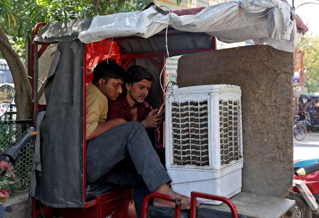 23日，印度两名男子坐在降温设备前。 （IC photo）