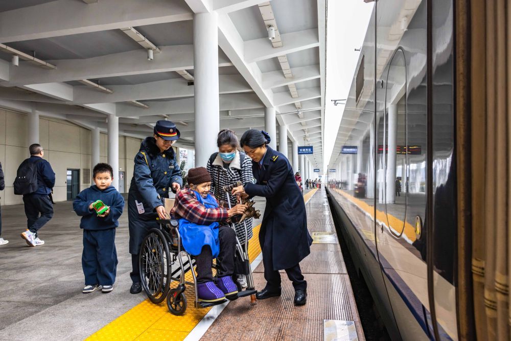 ↑ 1月25日,铁路工作人员在贵州安顺西站协助重点旅客乘车。新华社发(陈熙 摄)