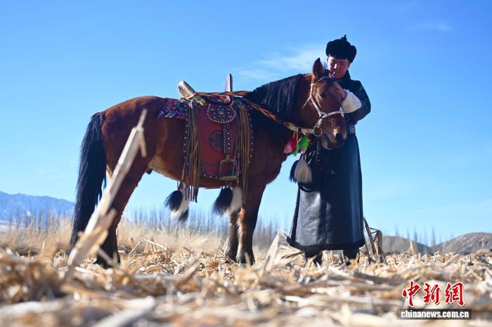 寒冬时节，甘肃省酒泉市肃北县党城湾镇浩布勒格村，年轻的养马人其乌抠每天骑马去草场给马匹拉水、投喂饲料。图为其乌抠和爱马。李亚龙 摄