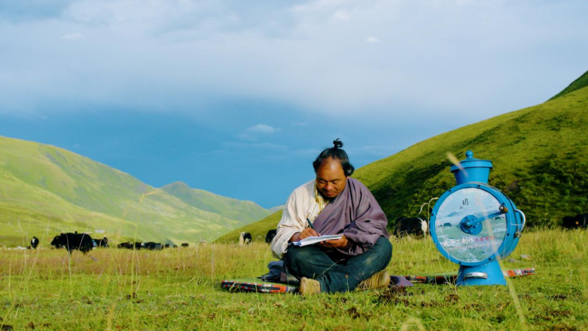 图为索县嘎美乡村民赤松和他发明的牛奶分离机。