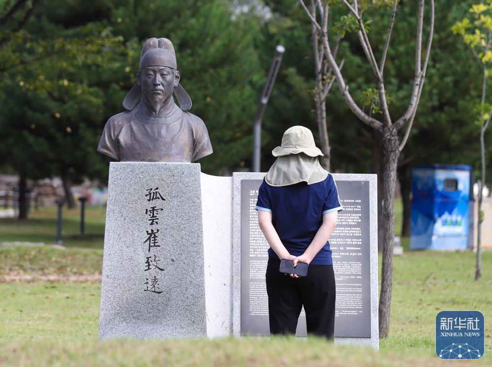 ↑2025年10月17日，市民在韩国庆州的“韩中友好林”公园里的崔致远铜像前观看崔致远的简介。崔致远是韩国历史上著名的文学家，被誉为“东国儒宗”。他12岁时离开故乡庆州，渡海赴大唐求学，18岁便中“宾贡进士”，后在扬州任职四年多。