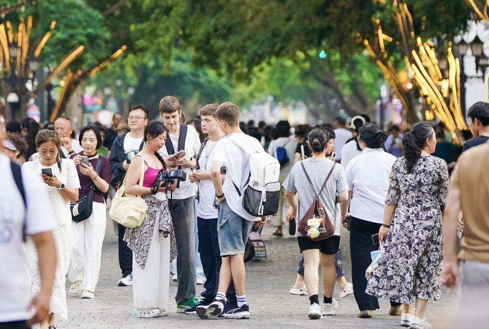 ↑ 7月22日,外国游客在哈尔滨中央大街参观游览。新华社记者 那宇奇 摄
