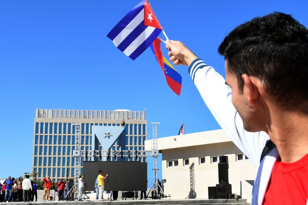 1月3日,在古巴首都哈瓦那,一名抗议者手持古巴和委内瑞拉国旗站在美国驻古巴大使馆前。