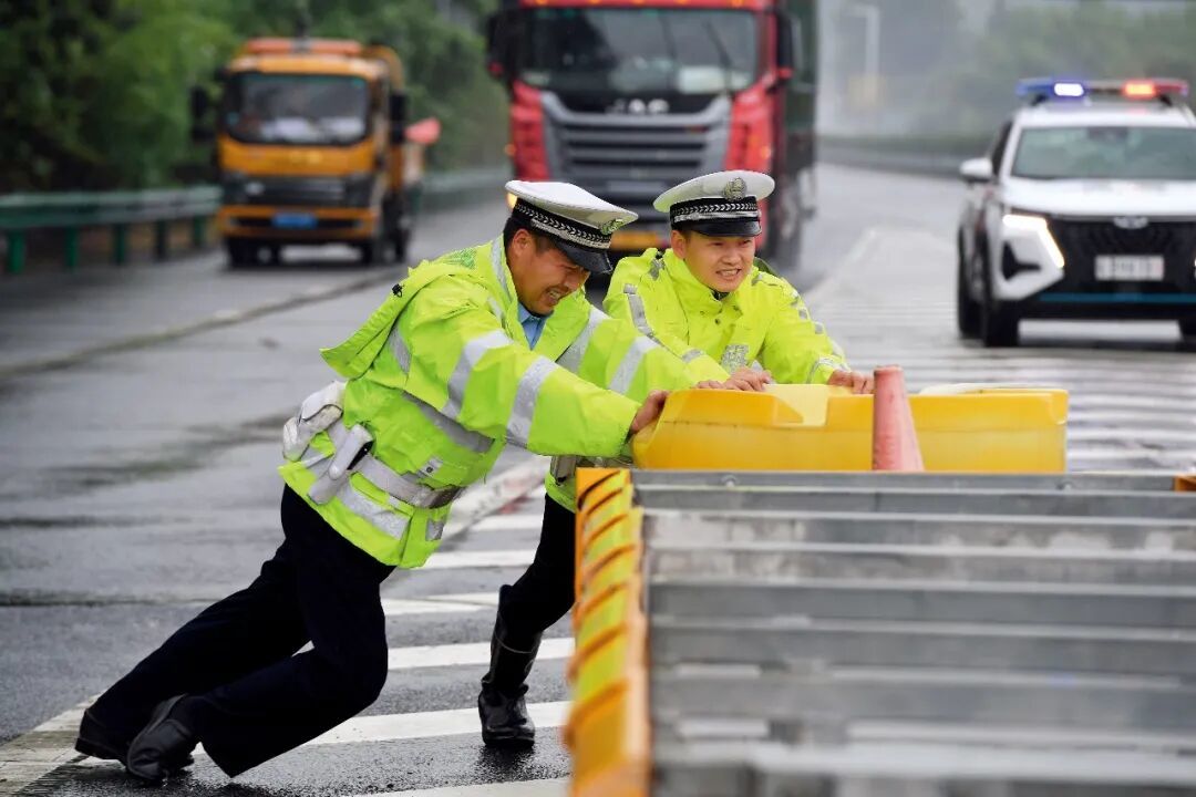 上图7月13日,沈阳市公安局皇姑分局鸭绿江派出所民警(左二)和消防员一起救助被困车辆。图/新华