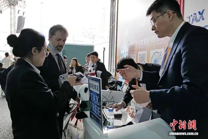 在第八届中国国际进口博览会举办期间,上海市税务局在展会现场首次设立离境退税“即买即退”集中退付点,在文创馆门口,工作人员协助外籍人员办理离境退税手续。中新社记者殷立勤摄