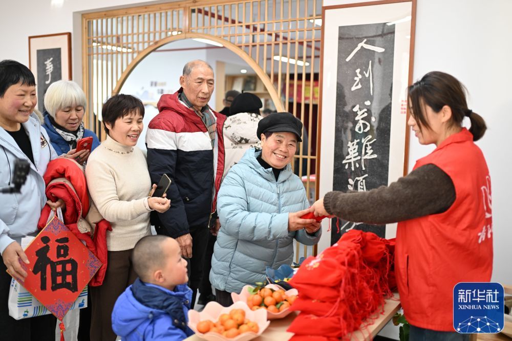 ↑ 1月22日，居民在江苏省昆山市昆苑社区新时代文明实践站领取新年福袋。新华社发（王须中摄）