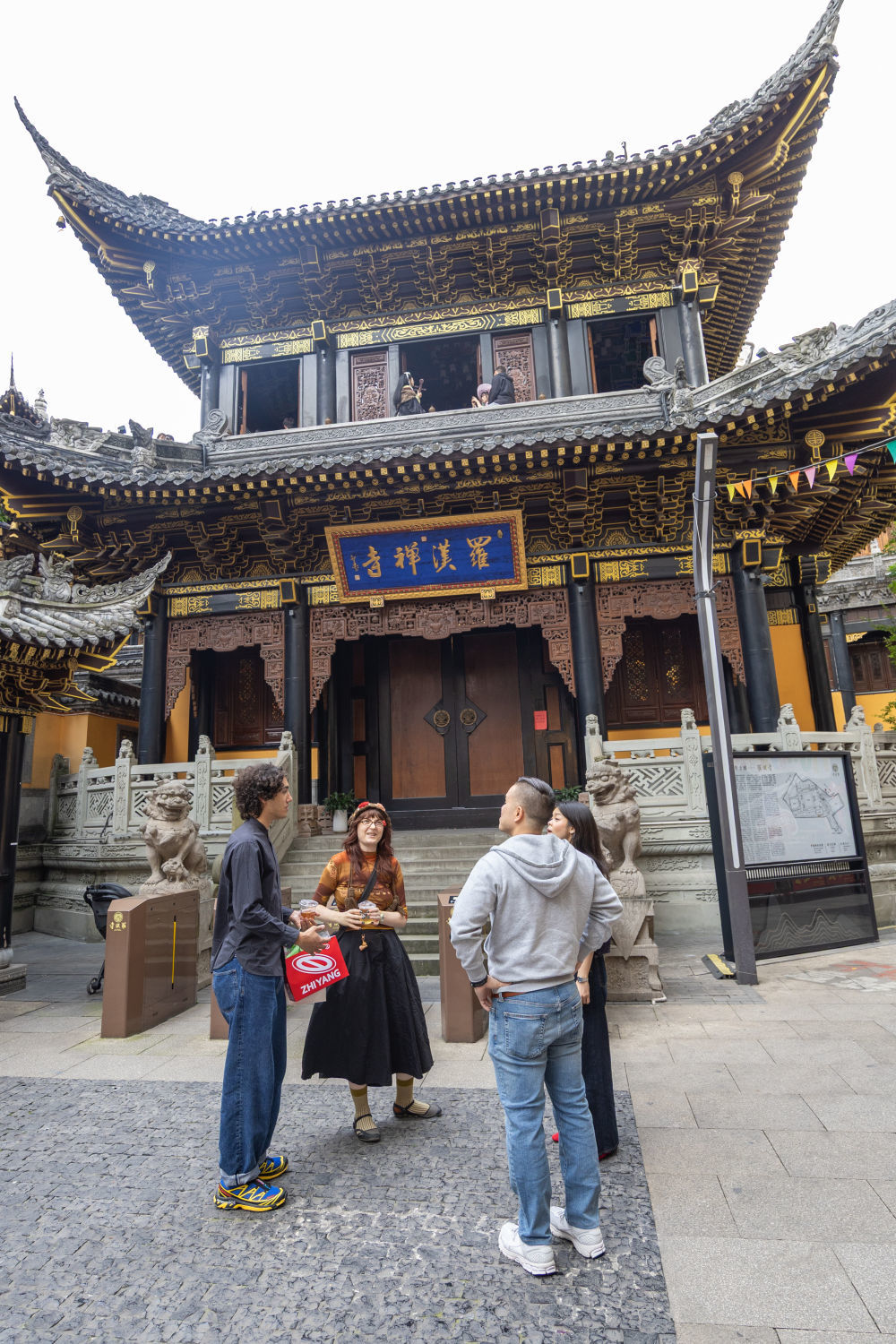 ↑ 4月22日，在重庆市渝中区妙街，来自美国和加拿大的游客在街边交流。