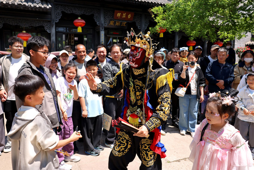 5月3日，在山东省枣庄市台儿庄古城，艺人与游客互动。新华社发（孙中喆摄）