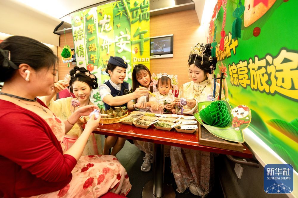 ↑ 6月16日,南昌至上饶G5030次列车上,身着汉服的工作人员和旅客一起制作端午香囊。新华社发(鲍赣生摄)