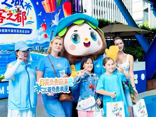 9月24日,在三亚凤凰国际机场国际到达口,外国旅客收到暖心礼包后,开心地与“椰宝”合影。李少云 摄