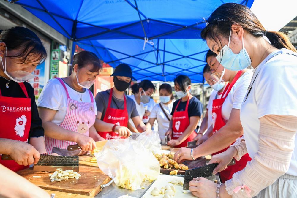 7月19日,志愿者在重庆彭水县山体崩塌救援现场附近的一处“爱心食堂”备菜。