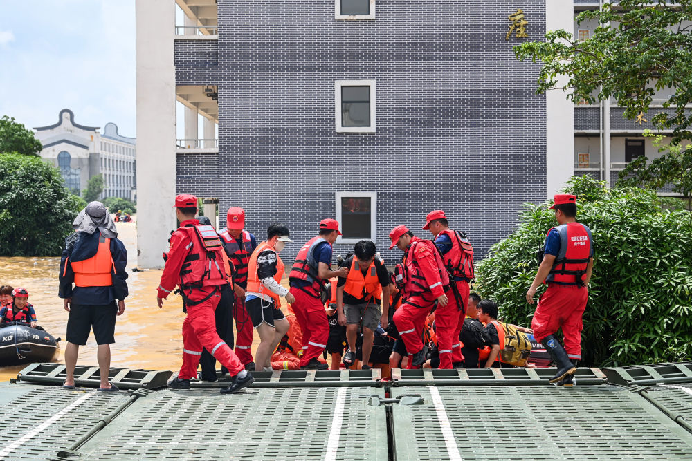 ↑ 7月9日,在广西贵港市西江教育园区,救援人员协助受困学生登上动力舟桥。新华社记者 曹祎铭 摄