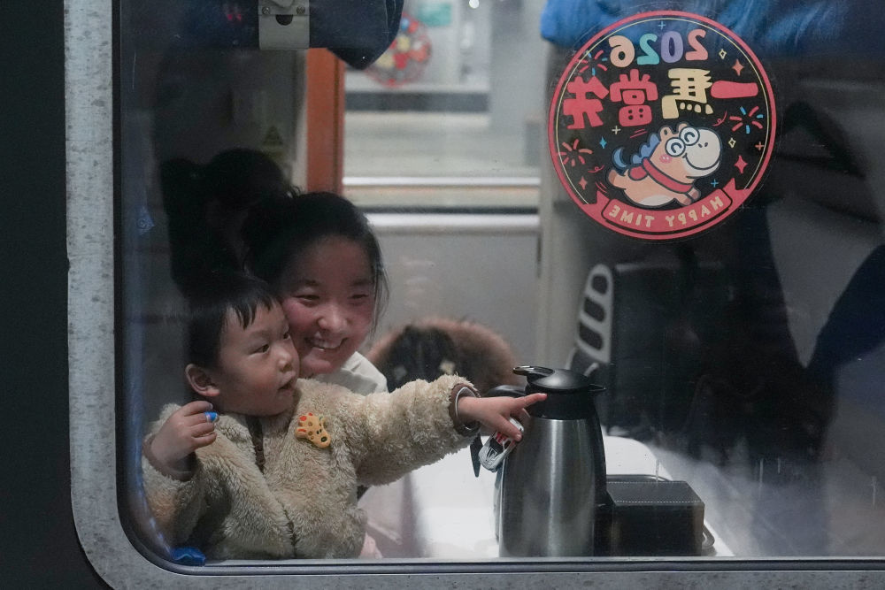 2月2日凌晨,在北京西站,2岁的小朋友吉祥(前)跟随妈妈一起乘坐K4069次列车返回阜阳老家过年。新华社记者 鞠焕宗 摄