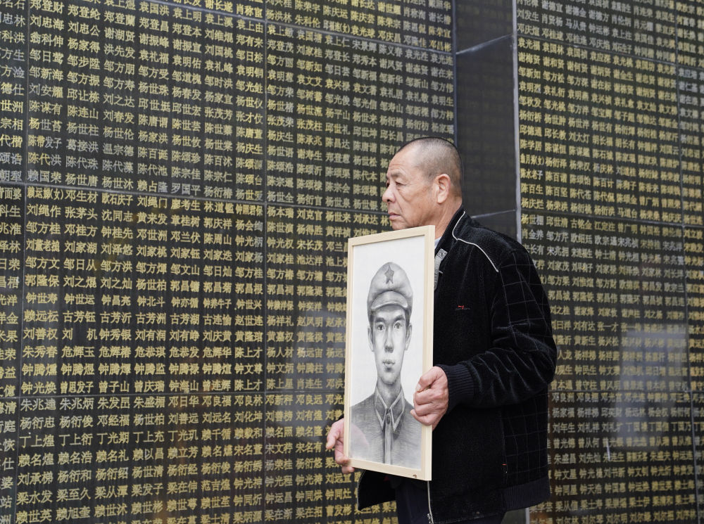 在瑞金革命烈士陵园，烈士家属手捧画像从烈士名单前走过（4月1日摄）。