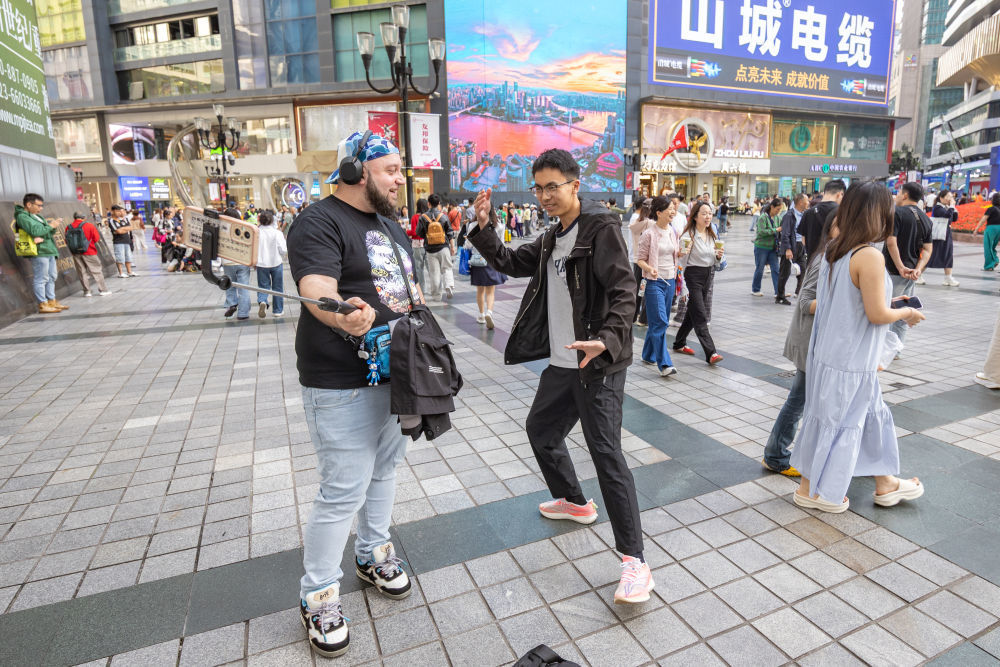 ↑ 4月22日，在重庆市渝中区解放碑商圈，一名荷兰游客（左）和一名中国博主交流。