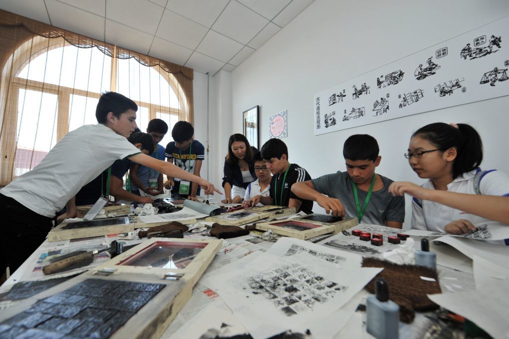2014年8月14日，在天津国际汉语学院，来自塔吉克斯坦的中学生在与中国学生一起体验活字印刷术。