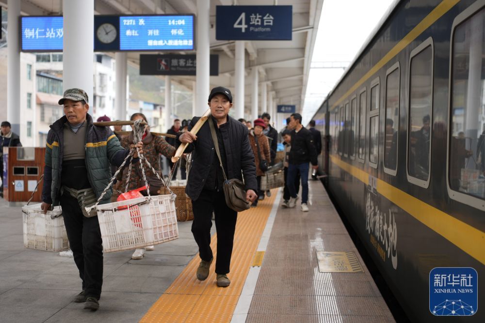 ↑ 2月12日,在贵州省铜仁市铜仁站,来自湖南的村民挑着售空的箩筐,准备乘坐7271次公益“慢火车”返程。新华社记者 刘续 摄
